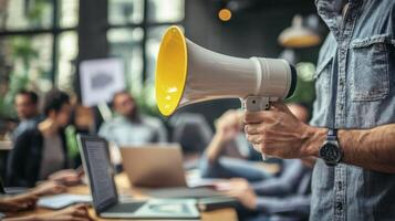 A man holding a megaphone in a busy office setting, with colleagues in the background. photo