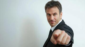 A man in a suit pointing at the camera with a serious expression. photo