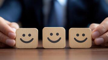 A person in a suit holding three wooden blocks with smiley faces on them, arranged in a row on a wooden table. photo