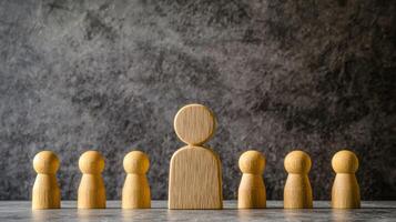 A wooden figure of a person standing in front of a group of smaller wooden figures, all facing the same direction, against a dark background. photo