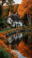 Charming thatched cottage beside tranquil lake surrounded by autumn foliage at golden hour photo