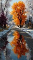 Vibrant autumn tree reflects in a serene puddle along a snowy path in a tranquil landscape photo
