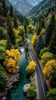 Beautiful autumn landscape featuring a winding road alongside a river in a mountainous area with vibrant foliage photo
