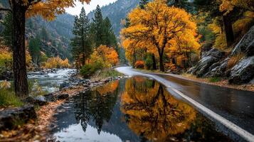 Autumn landscape with reflections in a river along a winding road amidst colorful foliage in a serene mountain setting photo