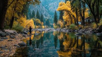 Woman stands by tranquil river reflecting autumn colors in serene landscape during golden hour photo