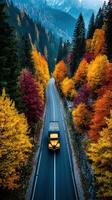 Truck driving through colorful autumn forest on winding mountain road photo