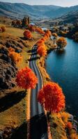 Scenic autumn drive along a river with vibrant orange trees in mountainous landscape during golden hour photo