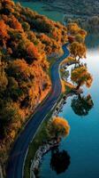 Serene autumn landscape with winding road beside tranquil lake and colorful foliage in a picturesque setting photo