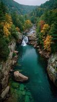Autumn colors surround a serene waterfall and river in a mountainous landscape during the fall season photo
