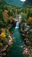 Majestic waterfall cascades through vibrant autumn foliage in serene mountain landscape photo