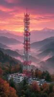 Sunrise over communication tower in mountains with colorful sky and fog photo