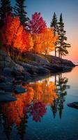Beautiful autumn landscape at sunset with colorful trees reflecting on calm water photo
