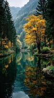 Autumn colors reflect on calm water in a serene forest landscape near a mountain photo