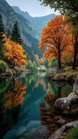 Autumn leaves reflect in tranquil river surrounded by mountains and trees photo