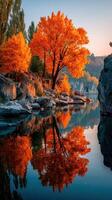 Vibrant autumn colors reflect on tranquil river at dawn near rocky cliffs photo