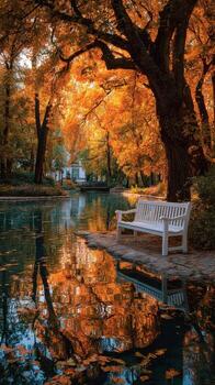 Autumn leaves reflect on tranquil water beside a white bench in a serene park setting during golden hour photo