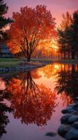 Autumn sunset reflects vibrant colors on calm water near trees and a house photo