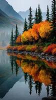 Colorful autumn foliage reflected in calm water near mountains at dawn photo