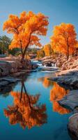 Vibrant autumn trees reflect in calm waters at a serene landscape under clear blue skies photo