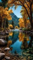 Autumn landscape with vibrant yellow trees and calm river reflecting the blue sky in a serene mountain setting photo