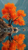Vibrant orange tree reflects beautifully in still lake at golden hour in a serene mountainous landscape photo