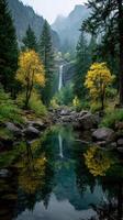 Waterfall cascades down rocky cliffs surrounded by autumn trees in misty mountain landscape photo