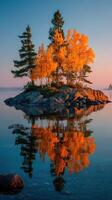 Vibrant autumn foliage reflects on calm water at dawn near a small island in a tranquil setting photo
