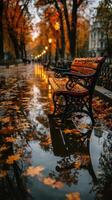 Rain creates a serene atmosphere around a park bench surrounded by autumn leaves in a golden-hued urban landscape photo