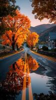 Autumn road lined with vibrant trees reflecting in puddles during sunset in a scenic valley photo