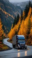 Truck driving through winding road surrounded by vibrant autumn foliage near mountains in a serene landscape photo