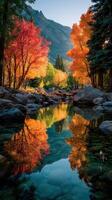 Autumn colors reflect in a tranquil stream surrounded by vibrant trees in a mountainous landscape during sunset photo