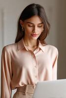 Woman working on laptop while wearing a stylish blouse photo