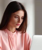 Focused woman working on laptop in a bright room photo