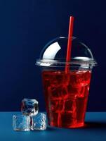Refreshing drink with ice cubes in a clear cup on blue background photo