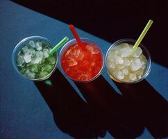 Refreshing drinks with ice in colorful cups on a table photo