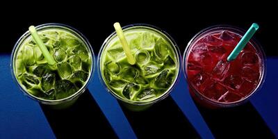 Colorful drinks in clear cups with ice against a blue background photo