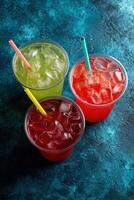 Colorful drinks with ice on a blue surface photo