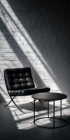 A black leather chair and table in front of a white brick wall photo