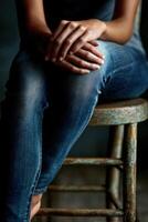 Casual pose in faded jeans on a rustic wooden stool photo