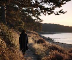 Viking woman walking along a coastal path at sunset in a forested area photo