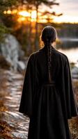 Viking woman enjoying a sunset by the water's edge in a forested area photo