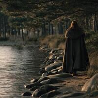 Viking woman walks along a riverbank in a serene forest setting photo
