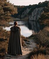 Viking woman standing near a serene river surrounded by cliffs photo