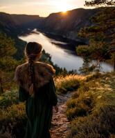 Viking woman standing on a path overlooking a serene fjord at sunset photo