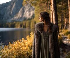 A woman in a fur coat stands by a lake photo