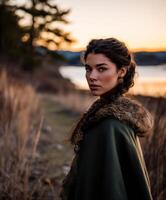 A woman in a cloak standing in front of a lake photo