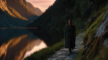 Viking woman walking along a serene lake at sunset in the mountains photo
