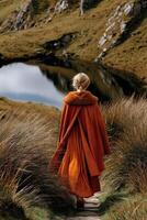 Viking woman walking through a serene landscape near a tranquil pond photo