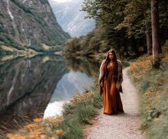 Viking woman in an elegant dress walking by a tranquil riverbank photo
