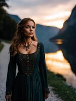 Viking woman stands by a serene lake during sunset in the mountains photo